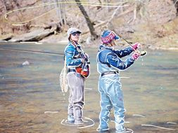 Anne and Kim fly fish in a shallow stream