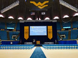A stage and empty chairs are organized on the floor of the coliseum prior to the beginning of commencement