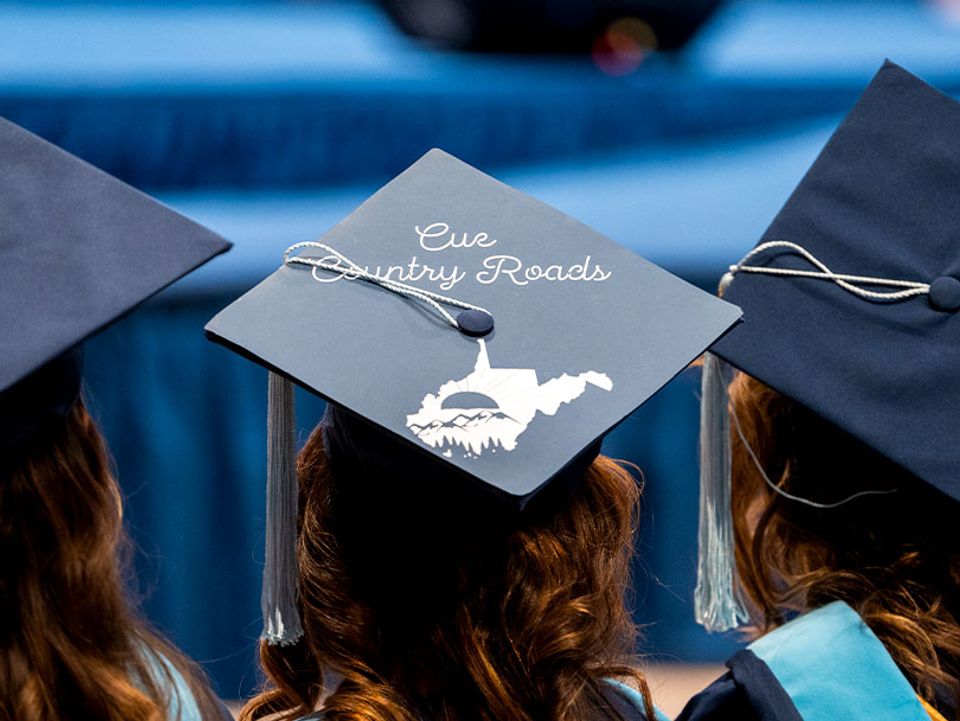
              Graduating students observe commencement, one students hat says 