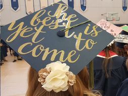 A graduating student whose hat says "the best is yet to come"