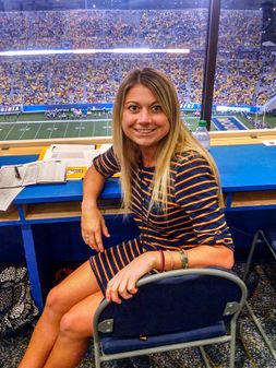 Samantha sitting in the press box at mountaineer field during a game