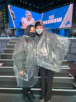 Madison Reeser in clear rain poncho with another event volunteer at NFL Draft event.
