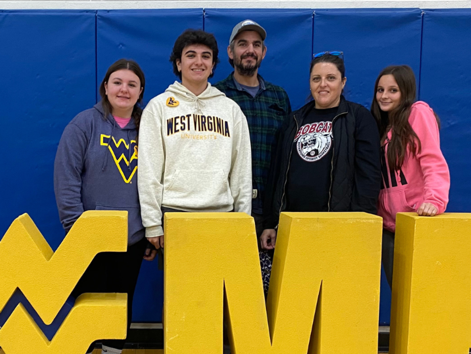 
              Tyler Derkotch poses with his family in front of a WVU 