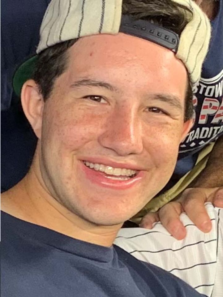
              Zach Kirschner smiling, wearing dark blue t-shirt, striped baseball cap on backwards.
            