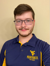 
              Daniel Thompson wearing gold and blue WVU themed knit shirt and glasses.
            