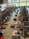 Clinic leaders are training student-athletes in large room with weight equipment while attendees watch the training session.
