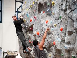 Student climbing rock wall with assistance from CPASS students