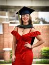 
              Yamile Gonzalez wears a red dress with ruffles, master's hood around her neck and graduation cap.
            