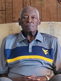 James L. Taylor seated and wearing a WVU branded knit shirt. 