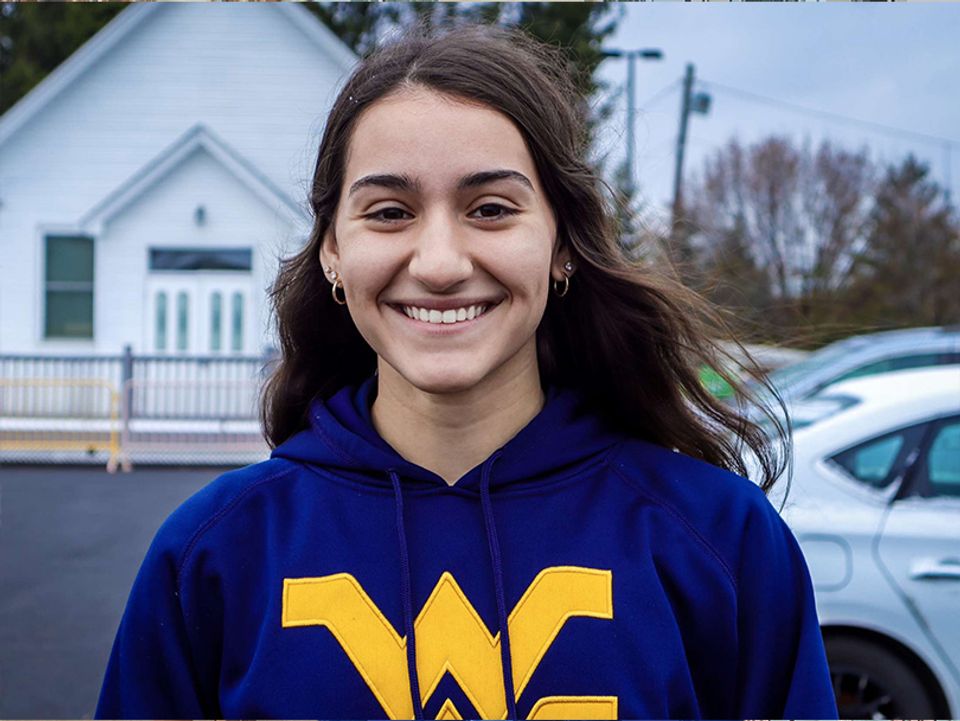 
              Maria Vito standing outside, with dark long hair and wearing a WVU blue hoodie. 
            