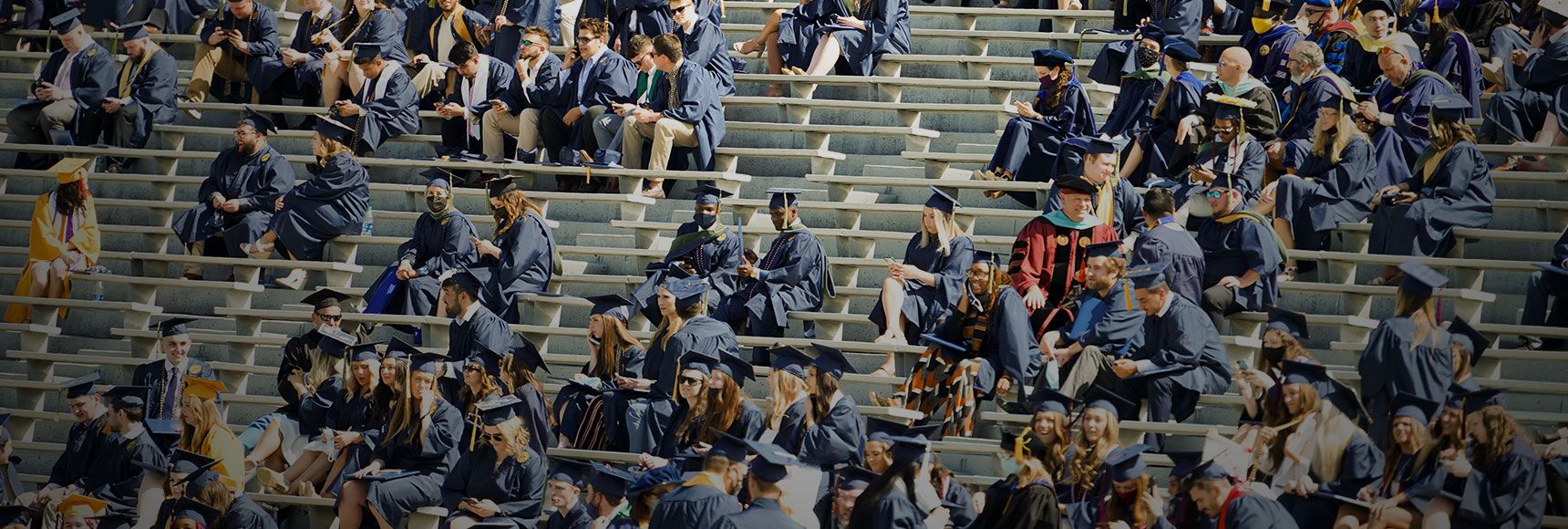 Graduated students watch commencement ceremony from the stands of mountaineer field